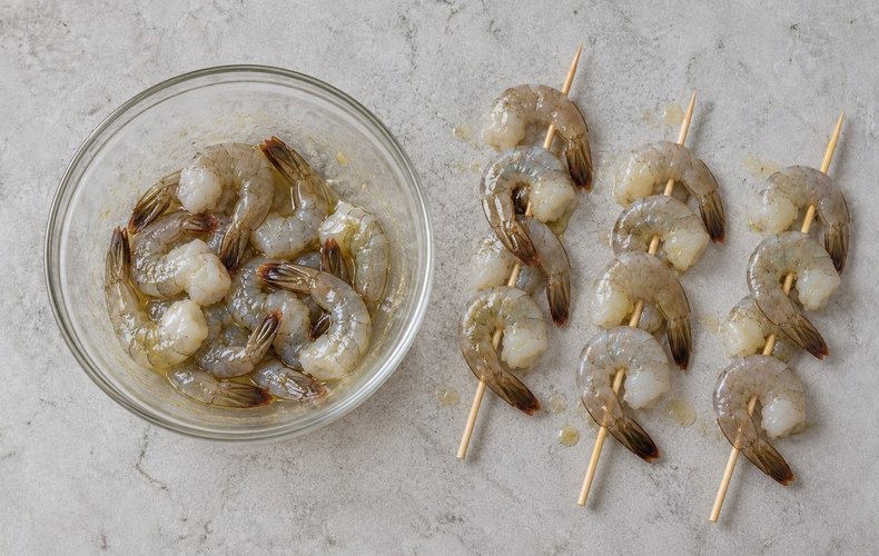 Air Fryer Shrimp Skewers, step 2: shrimp coated in olive oil and threaded onto wooden skewers