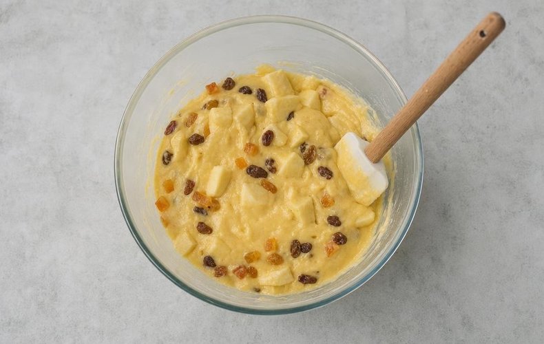 Folding candied fruit, raisins and apple chunks into the batter