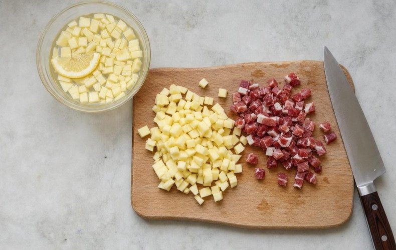 Apple and Speck Risotto, step 1: diced speck and apples in a bowl of lemon water