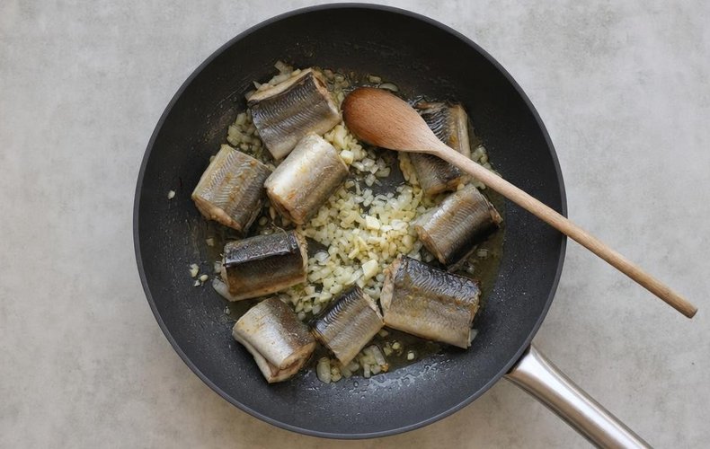 Calabrian Capitone Eel in Tomato Sauce, step 2: capitone pieces browning in a skillet with onion and garlic