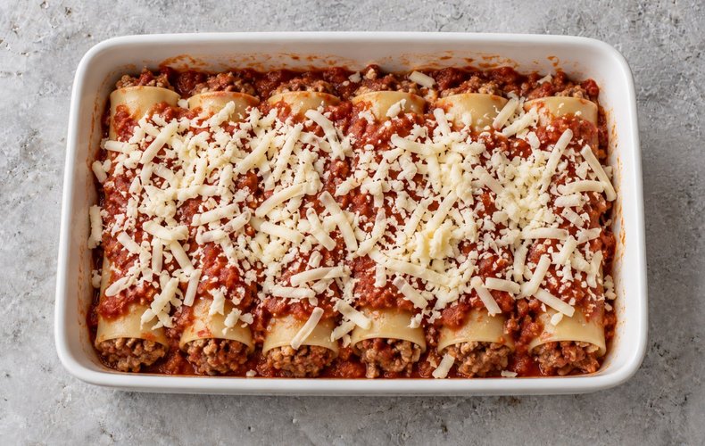 Calabrian Stuffed Schiaffettoni, step 6: stuffed cannelloni in a baking dish with sauce and grated provola