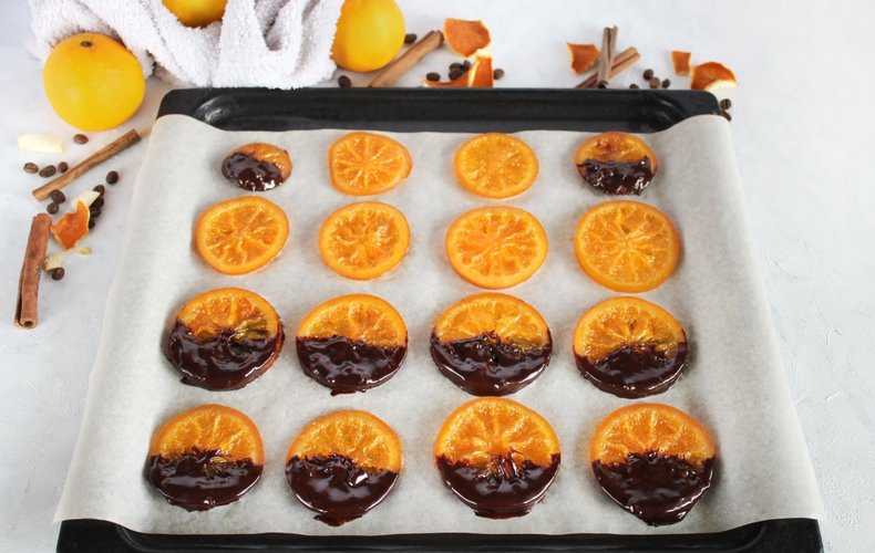 Chocolate-dipped orange slices setting on parchment paper