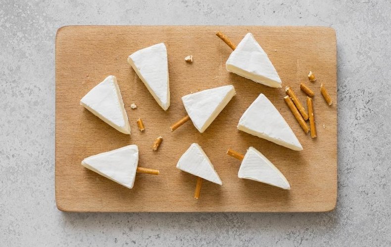 Cheese Christmas Trees, step 2: pretzel sticks pushed into the cheese triangles as trunks