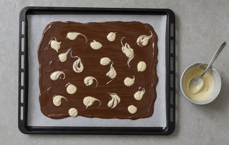 Chocolate Bark with Nuts and Berries, step 3: spoonfuls of melted white chocolate on the milk chocolate