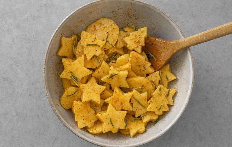 Seasoning the potato shapes with oil, spices and rosemary