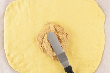 Cinnamon filling spread over the rolled-out dough