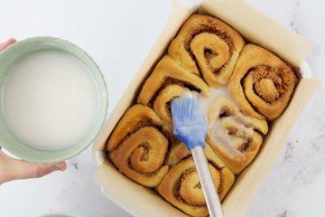 Brushing glaze over the cinnamon rolls