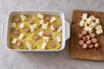 Creamy Cheese Potatoes, step 2: layering potatoes, cheeses and frankfurters in a baking dish