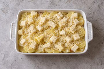 Creamy Cheese Potatoes, step 3: layered potatoes topped with mozzarella and Parmigiano in a baking dish