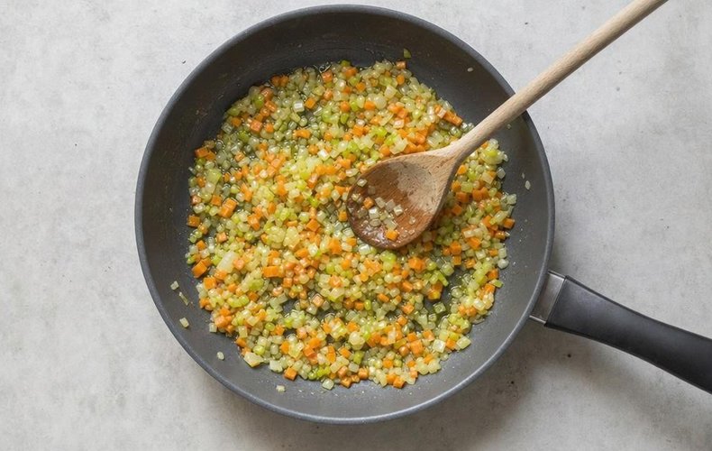 Creamy Lentil Soup with Crispy Bacon, step 1: chopped carrot, onion and celery sautéing in a pan