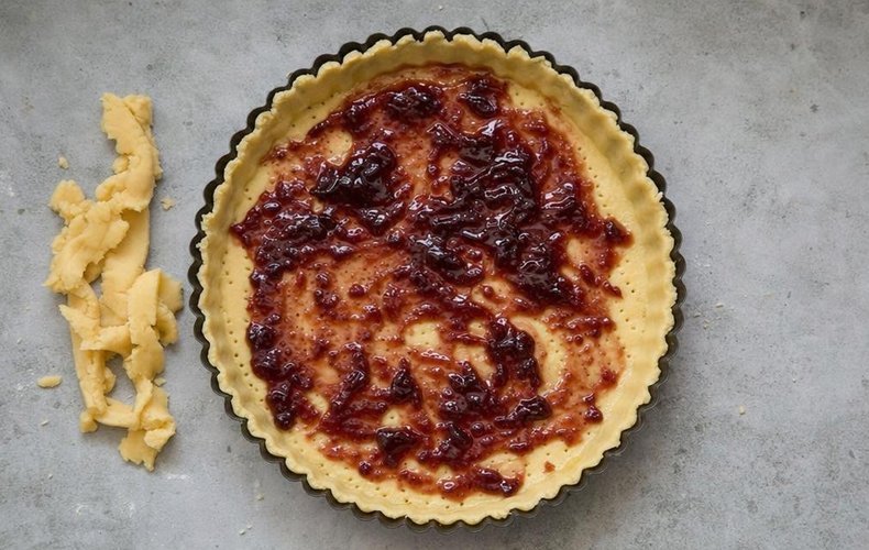 Don Camillo Tart, step 3: plum jam spread over the shortcrust in the tart pan