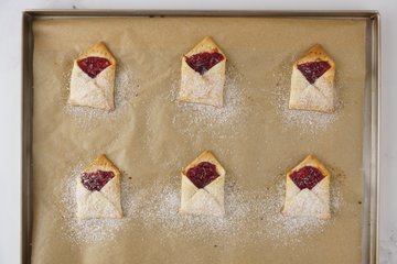 Pastry envelopes dusted with powdered sugar and topped with fondant seals
