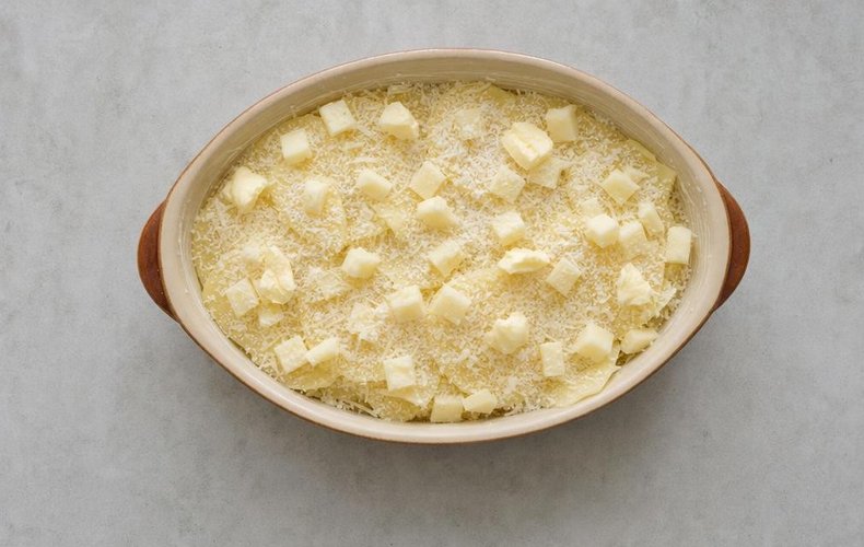 Four Cheese Potatoes, step 3: the layers topped with grated cheese and pats of butter