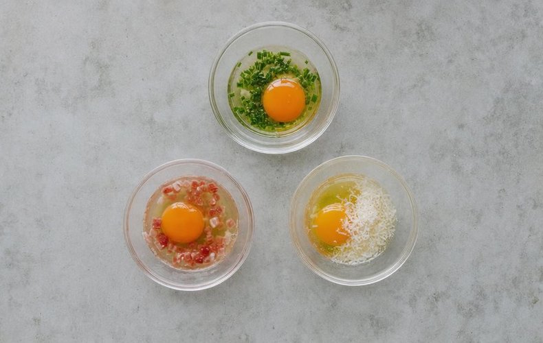 Frittata-in-a-Hole Toasts, step 2: three bowls of egg with chives, pancetta and Parmigiano
