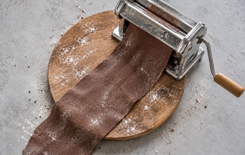 Rolling out the cocoa pasta dough with a pasta machine