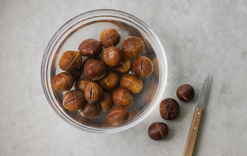 Homemade Marrons Glacés, step 1: chestnuts scored all around and soaking in water