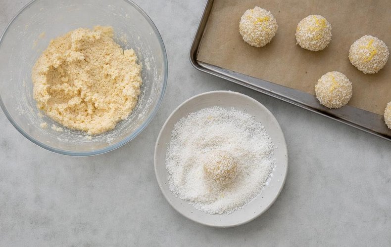 Lemon Coconut Truffles, step 4: balls of dough rolled in desiccated coconut on a tray