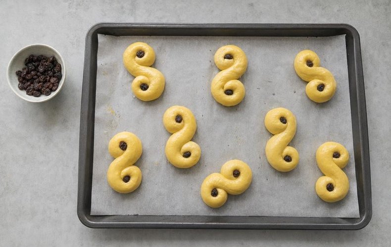 Lussekatter, step 5: the buns with raisins on the baking sheet