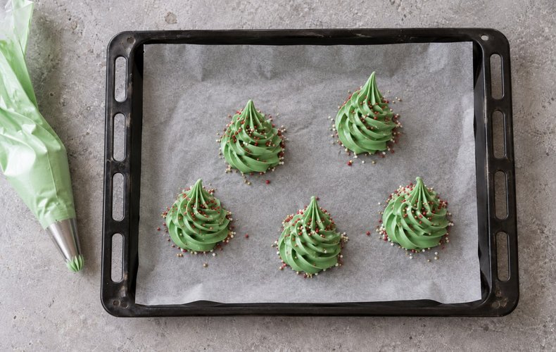 Meringue Christmas Trees, step 4: meringue trees piped onto parchment paper and decorated with sprinkles