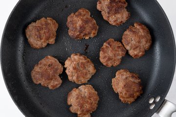 Balls of ground beef in a hot skillet