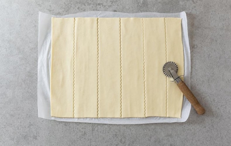 Cutting puff pastry into strips with a pastry wheel