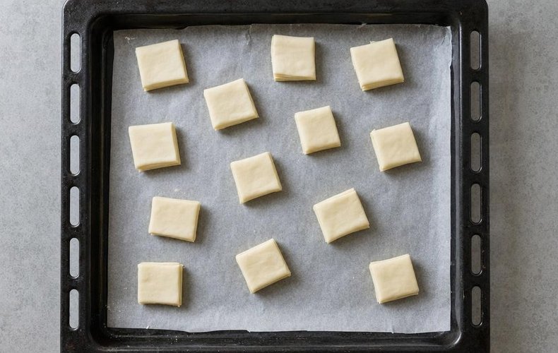 Small pieces of puff pastry on a lined baking sheet