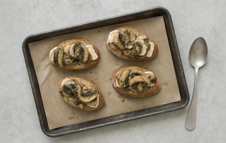 Mushroom and Brie Crostini, step 7: the crostini topped with mushrooms on a lined baking sheet