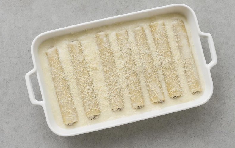 Mushroom Cannelloni, step 8: filled cannelloni in a baking dish covered with béchamel and Parmigiano