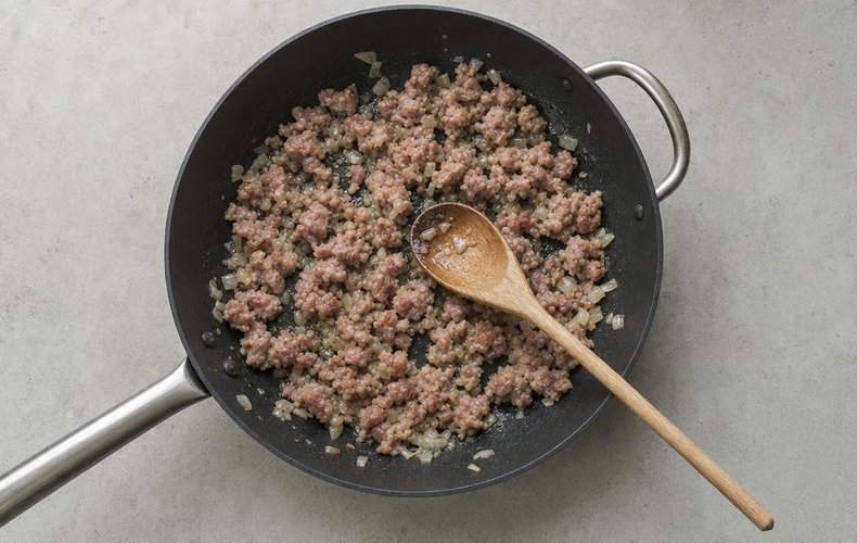 Pasta alla Carcerata, step 3: crumbled sausage browning with the onion