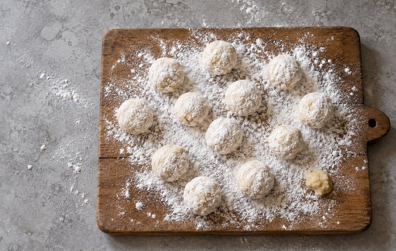 Prosecco Cookies, step 2: a piece of dough rolled into a ball on powdered sugar