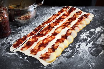 Overlapping apple slices along a puff pastry strip