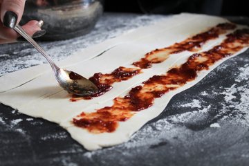 Spreading jam on the puff pastry strips
