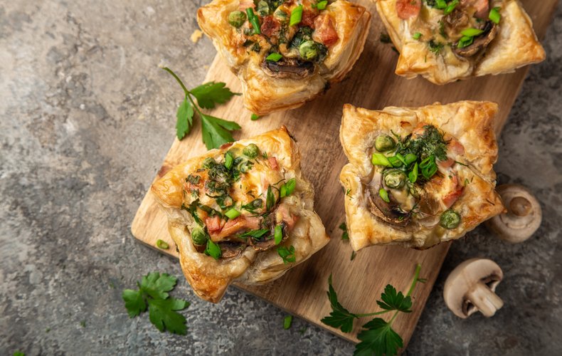 Puff pastry cups with ham and mushrooms on a cutting board