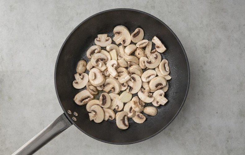 Puff Pastry Cups with Ham and Mushrooms, step 1: sliced mushrooms in a pan with oil and garlic