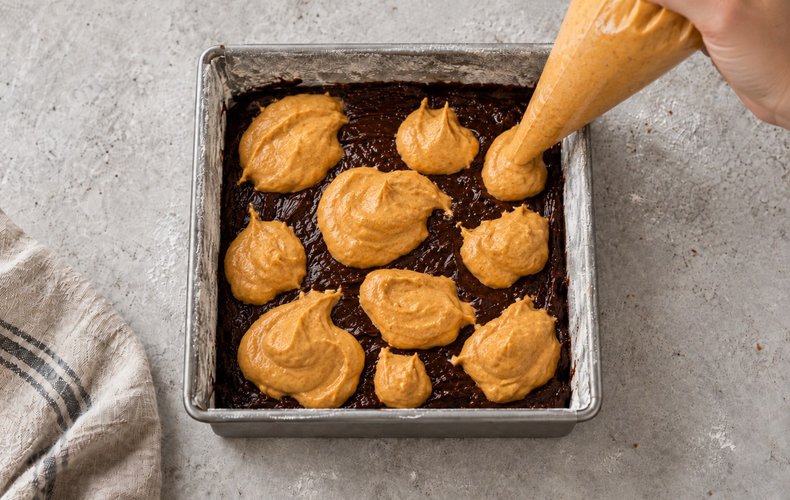 Pumpkin and Amaretti Cheesecake Brownies, step 8: cheesecake cream piped over the brownie batter