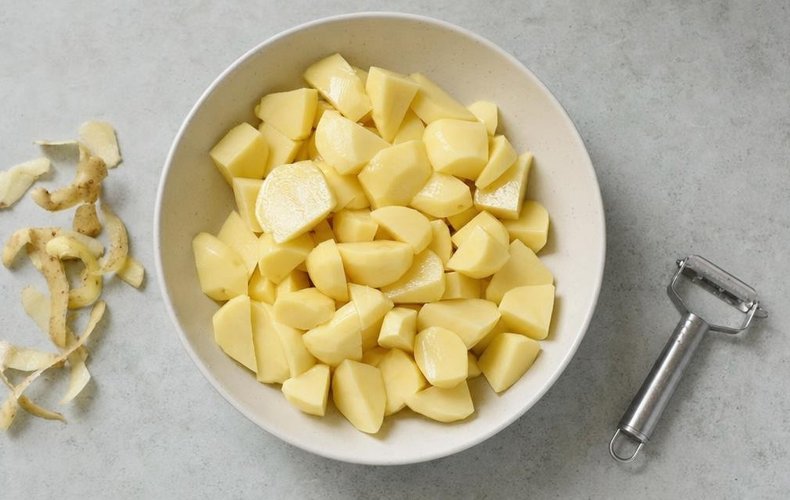 Roasted potatoes with garlic and onions, step 1: peeled potatoes cut into pieces in a bowl
