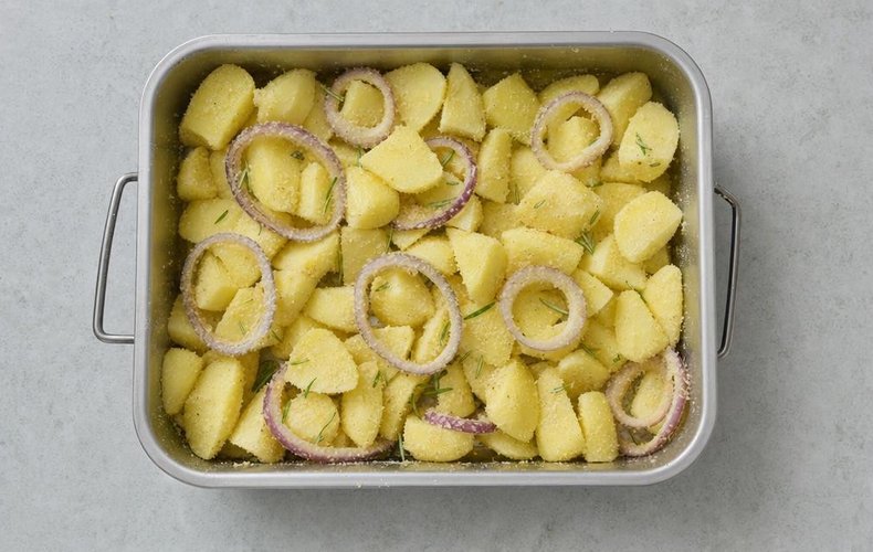 Roasted potatoes with garlic and onions, step 2: potatoes and onion rings in the baking dish