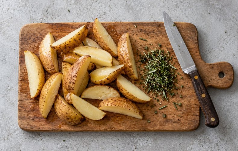 Roasted Potatoes with Pancetta, step 1: potatoes cut into wedges, with chopped rosemary and thyme