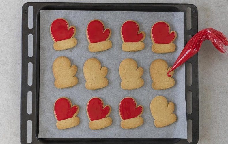 Santa's Mitten Cookies, step 8: the cookies being decorated with red and white icing