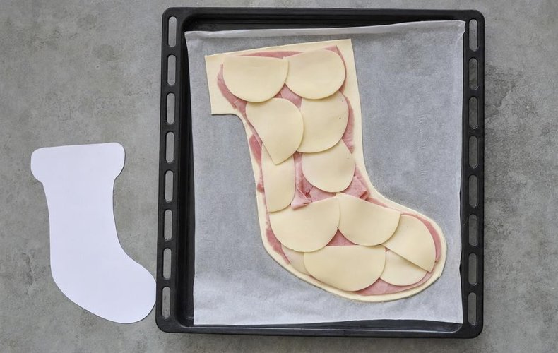 Savory Befana Stocking, step 2: ham and provola arranged in the shape of a stocking on the puff pastry