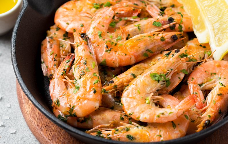 Whole jumbo shrimp cooked in a skillet with lemon