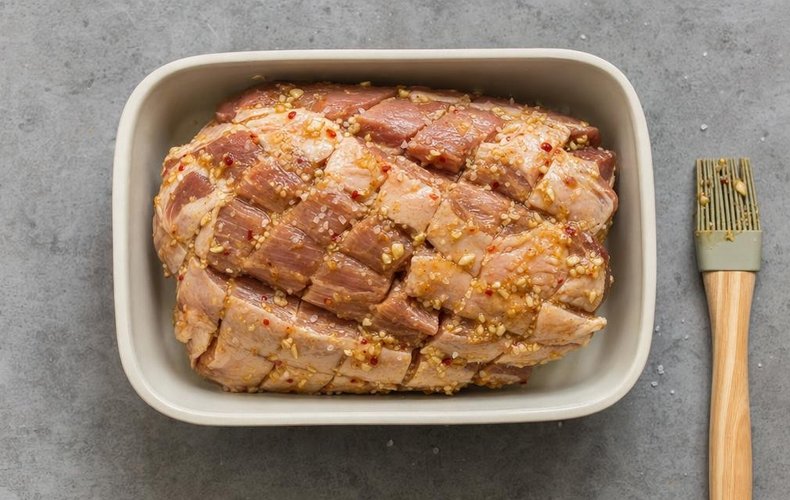 Slow-Roasted Pork Shoulder, step 2: scored pork shoulder brushed with the sauce in a baking dish