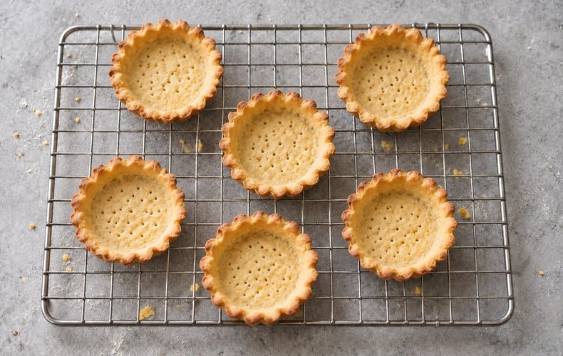 Baked tartlet shells cooling on a wire rack