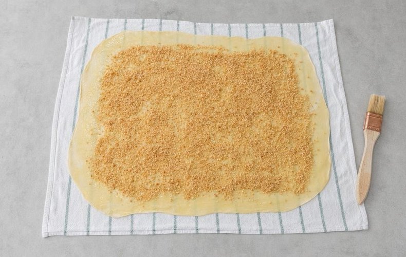Apple Strudel, step 9: dough brushed with butter and covered with toasted breadcrumbs