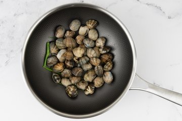Spaghetti with Clams and Cherry Tomatoes, preparation 2: clams cooking in a pan with garlic, parsley and white wine