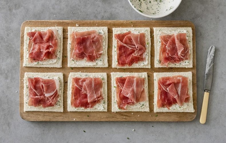 Flattened bread spread with chive cream cheese and topped with speck