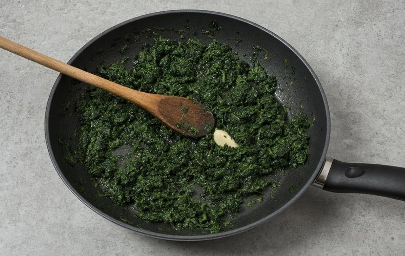 Spinach and Salmon Roll, step 1: chopped spinach cooking in a skillet with garlic