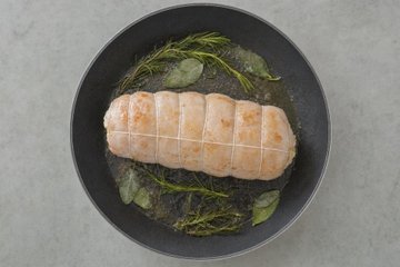 Stuffed Roast Turkey Roll, step 5: the turkey roll in a skillet with sage and rosemary