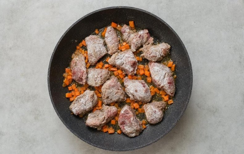 Veal Cheeks with White Wine and Porcini, step 2: floured veal cheek pieces browning with diced carrots